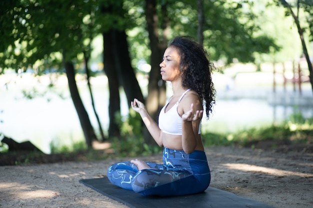 Giovane donna atletica che medita in un parco cittadino