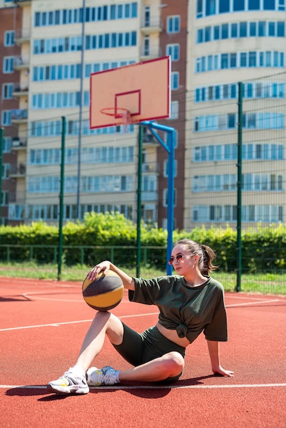 Giovane donna atletica che posa con una palla sul campo