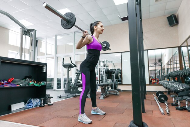 Giovane donna atletica che si esercita sulle macchine nella moderna palestra sportiva