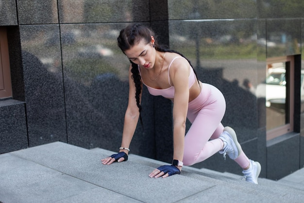 Giovane donna atletica che spinge su per le scale in un allenamento di strada in città