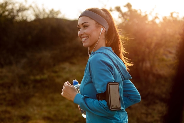 Giovane donna atletica felice che corre in natura al mattino