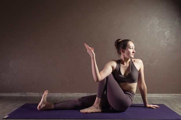 Giovane donna attraente a praticare yoga che indossa abiti sportivi