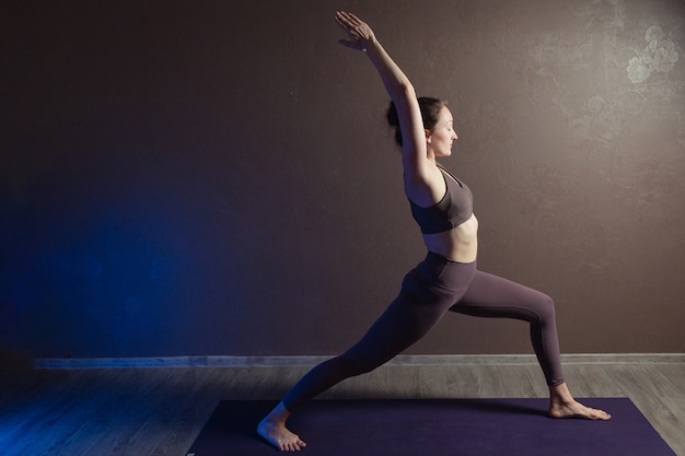 Giovane donna attraente a praticare yoga che indossa abiti sportivi