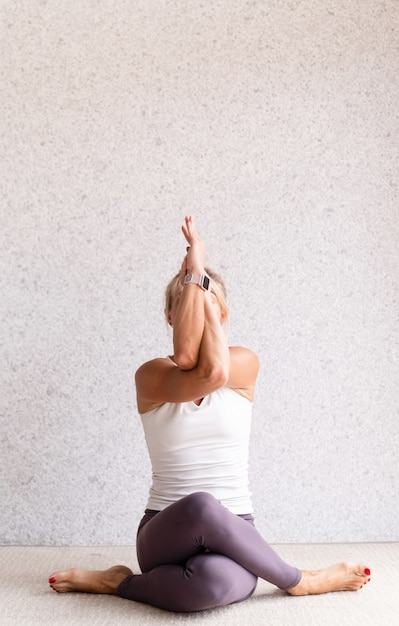 Giovane donna attraente a praticare yoga mentre indossa abiti sportivi al chiuso