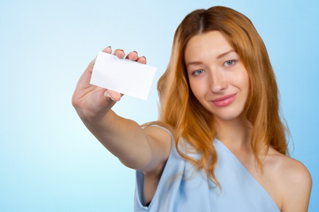 Giovane donna attraente allegra che mostra foglio di carta in bianco con lo spazio della copia