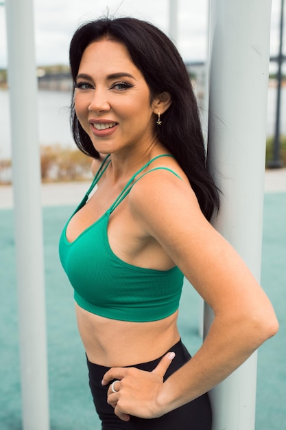 Giovane donna attraente bruna facendo esercizi e posa allo sportground all'aperto