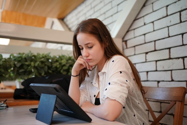 Giovane donna attraente che interagisce con il tablet mobile nella caffetteria