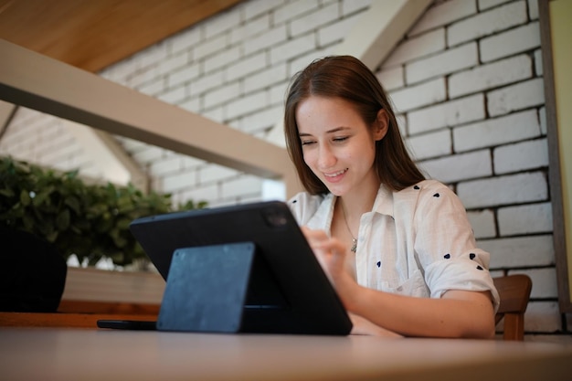 Giovane donna attraente che interagisce con il tablet mobile nella caffetteria