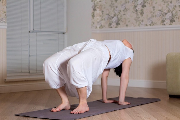 Giovane donna attraente che pratica yoga indossando abbigliamento sportivo sessione di meditazione interno domestico