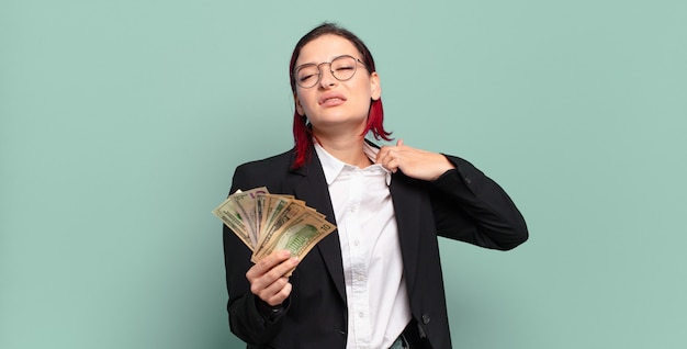 Giovane donna attraente con i capelli rossi che si sente stressata, ansiosa, stanca e frustrata, tira il collo della camicia, sembra frustrata dal problema. concetto di denaro