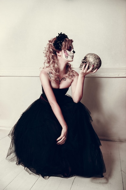 Giovane donna attraente con trucco del cranio dello zucchero. Giorno messicano della donna morta che indossa trucco teschio di zucchero e corona di fiori.