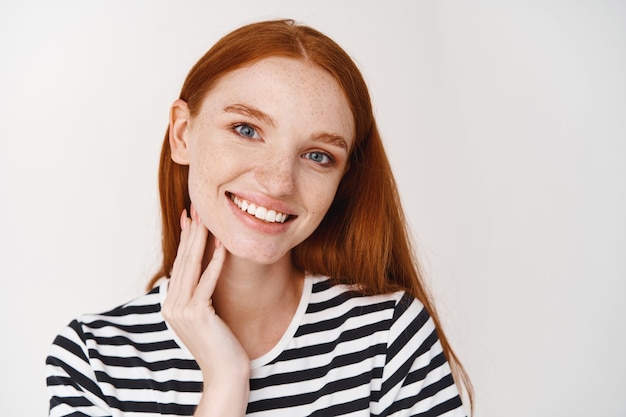 Giovane donna attraente dai capelli rossi che sorride guardando davanti