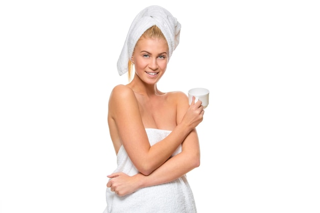 Giovane donna attraente in asciugamano che tiene una tazza