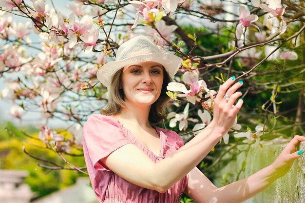 giovane donna attraente nel giardino di primavera. magnolie in fiore. Sfondo di primavera. Ritratto di stile di vita