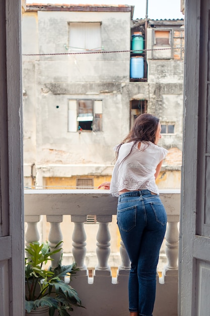 Giovane donna attraente sul vecchio balcone in appartamenti a L'Avana