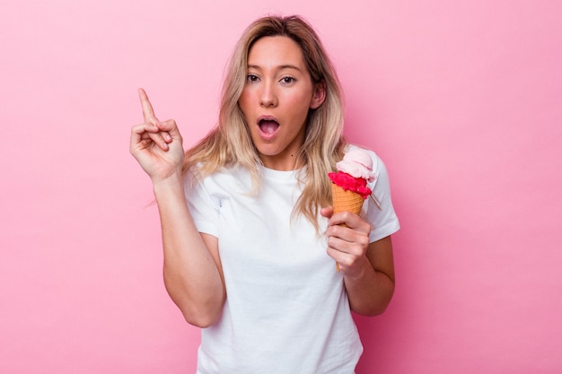 Giovane donna australiana che tiene un gelato isolato su sfondo rosa con qualche grande idea, concetto di creatività.