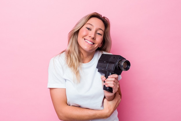 Giovane donna australiana riprese con una videocamera vintage isolata ridendo e divertendosi.