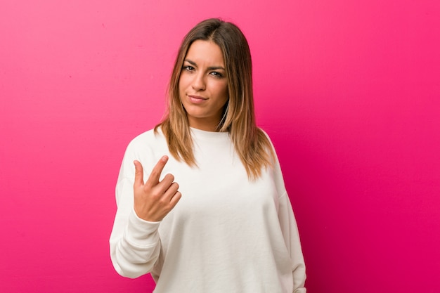 Giovane donna autentica carismatica vera gente contro un muro che punta con un dito contro di te come se l'invito si avvicinasse.