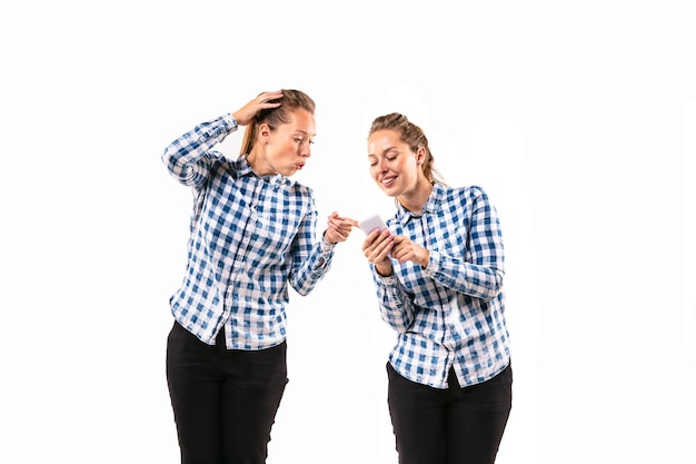 Giovane donna bella che discute con se stessa sul fondo bianco dello studio.