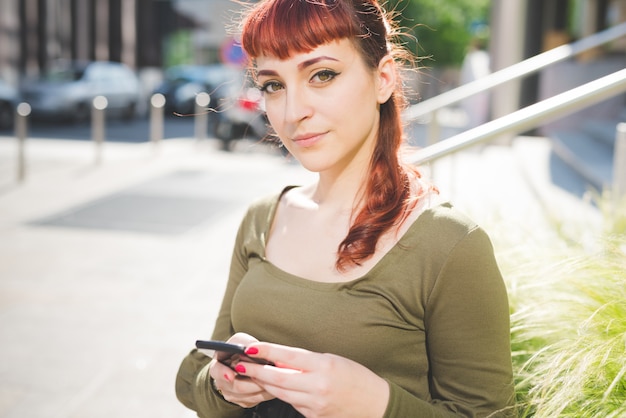 giovane donna bella rossa utilizzando smartphone