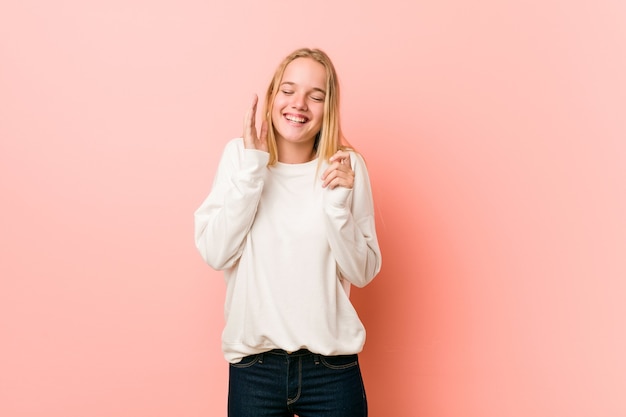 Giovane donna bionda adolescente gioiosa che ride molto. Concetto di felicità.