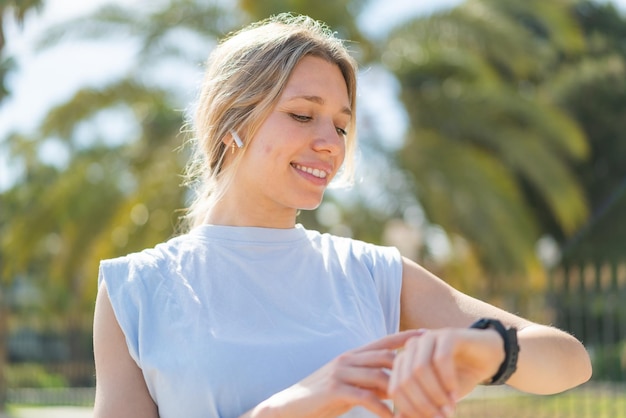 Giovane donna bionda all'aperto che fa sport con orologio sportivo