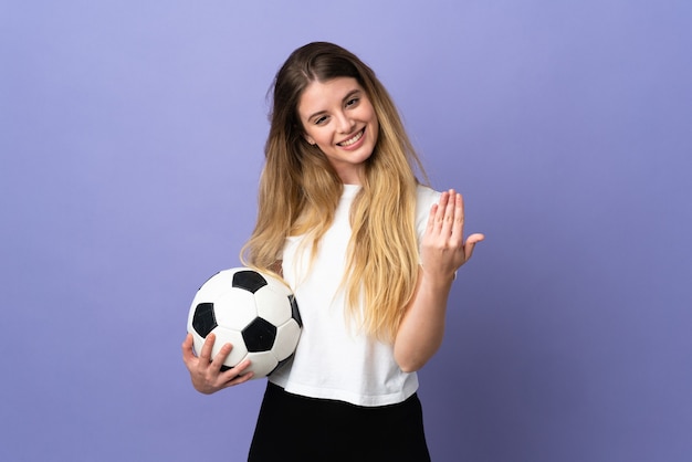 Giovane donna bionda calciatore isolata su spazio viola stringe la mano per chiudere un buon affare