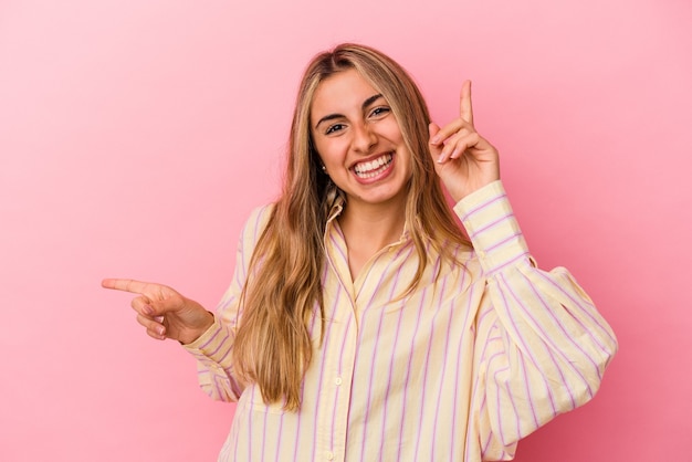 Giovane donna bionda caucasica che punta in direzioni diverse, scegliendone una, mostrando con il dito.