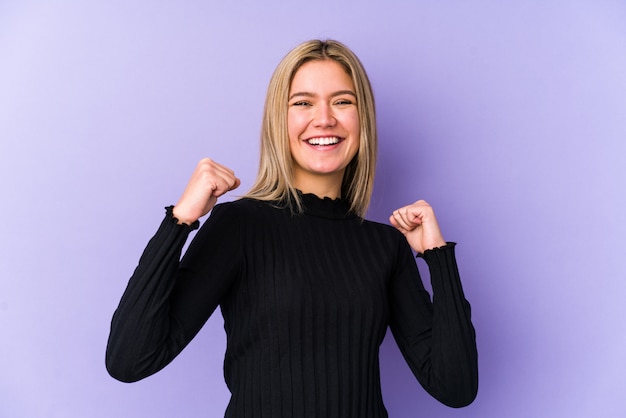 Giovane donna bionda che celebra una vittoria, passione ed entusiasmo, espressione felice