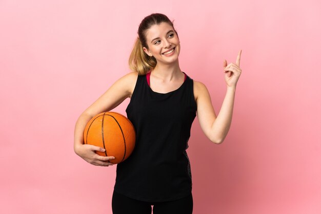 Giovane donna bionda che gioca a basket isolato sul muro rosa rivolto verso l'alto una grande idea