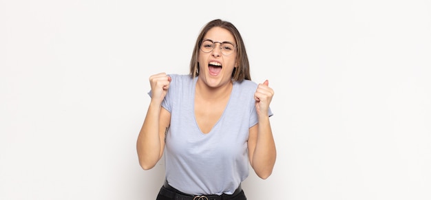 Giovane donna bionda che grida in modo aggressivo con un'espressione arrabbiata o con i pugni serrati per celebrare il successo