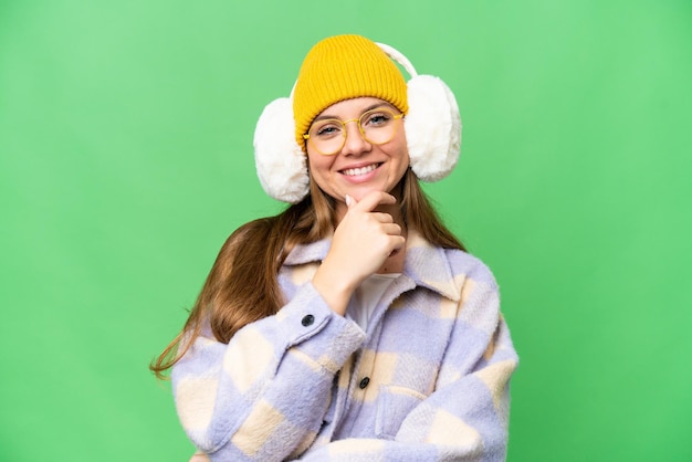 Giovane donna bionda che indossa manicotti invernali su sfondo chroma key isolato con occhiali e sorridente