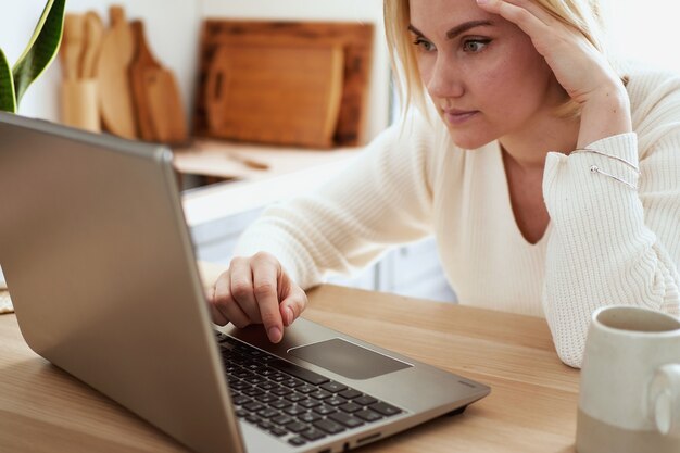 Giovane donna bionda che lavora al computer portatile a casa, shopping a casa