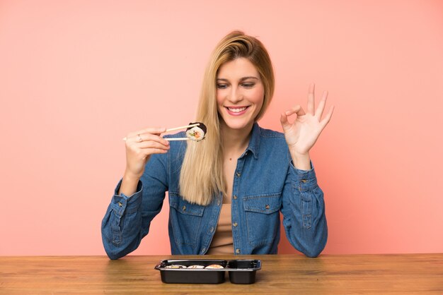 Giovane donna bionda che mangia i sushi