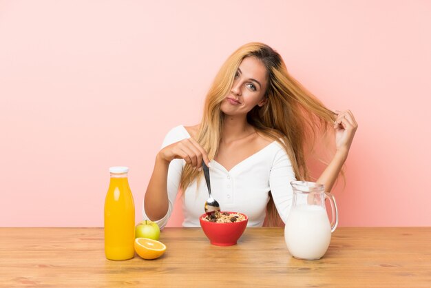 Giovane donna bionda che mangia il latte della prima colazione