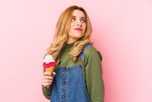 Giovane donna bionda che mangia un gelato che esamina un lato