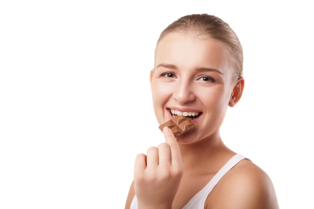 Giovane donna bionda che morde cioccolato isolato