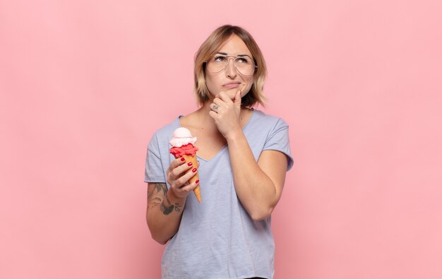 Giovane donna bionda che pensa, si sente dubbiosa e confusa, con diverse opzioni, chiedendosi quale decisione prendere