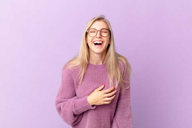 Giovane donna bionda che ride ad alta voce per uno scherzo esilarante