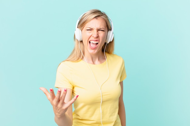 Giovane donna bionda che sembra arrabbiata, infastidita e frustrata e ascolta musica.