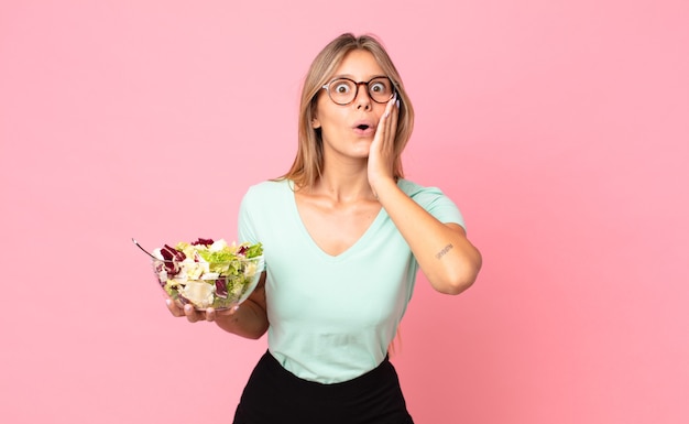 Giovane donna bionda che si sente scioccata e spaventata e tiene in mano un'insalata