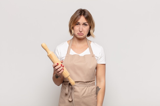 Giovane donna bionda che si sente triste e piagnucolona con uno sguardo infelice, piange con un atteggiamento negativo e frustrato