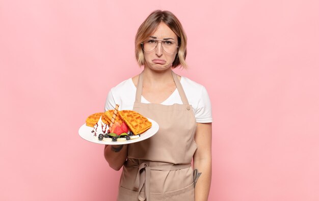 Giovane donna bionda che si sente triste e piagnucolona con uno sguardo infelice, piangendo con un atteggiamento negativo e frustrato