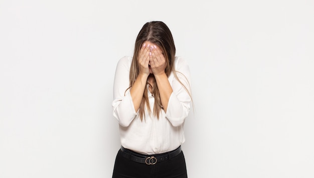 Giovane donna bionda che si sente triste, frustrata, nervosa e depressa, che copre il viso con entrambe le mani, piangendo