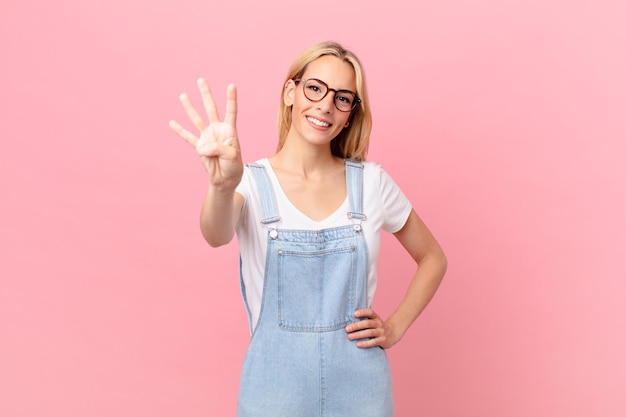 Giovane donna bionda che sorride e che sembra amichevole che mostra il numero quattro