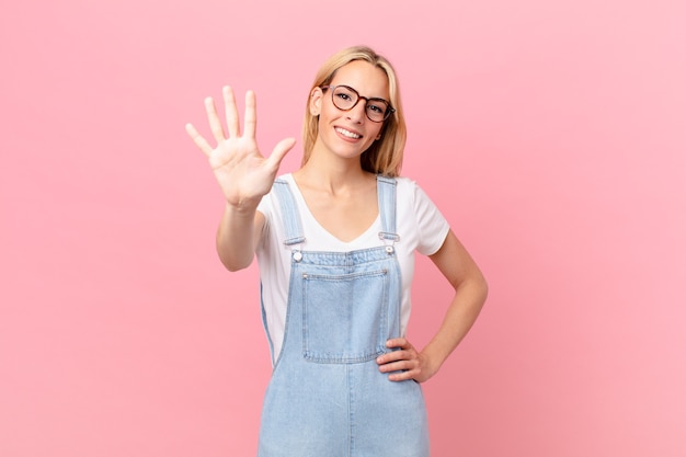 Giovane donna bionda che sorride e sembra amichevole, mostrando il numero cinque