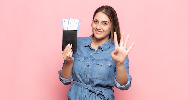 Giovane donna bionda che sorride e sembra amichevole, mostrando il numero quattro o quarto con la mano in avanti, conto alla rovescia