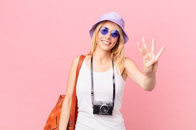 Giovane donna bionda che sorride e sembra amichevole, mostrando il numero quattro