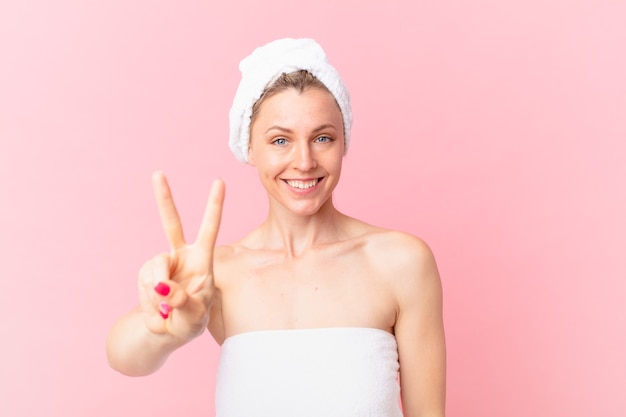 Giovane donna bionda che sorride e sembra felice, gesticola vittoria o pace e dopo la doccia