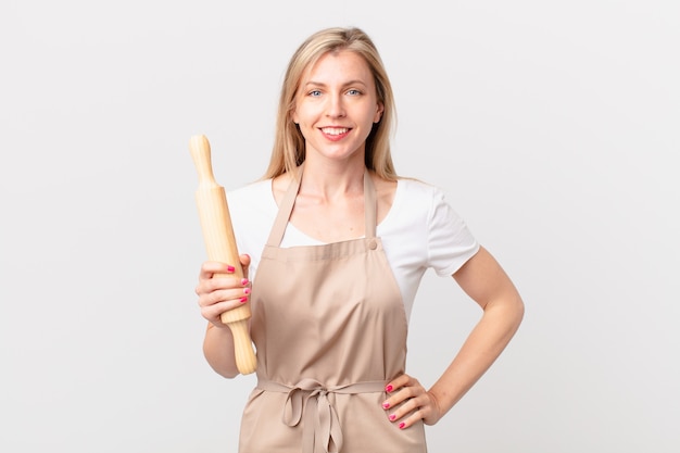 giovane donna bionda che sorride felicemente con una mano sull'anca e sicura di sé. concetto di panettiere